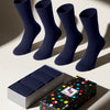 Four pairs of navy blue socks with a colorful polka dot box in the background