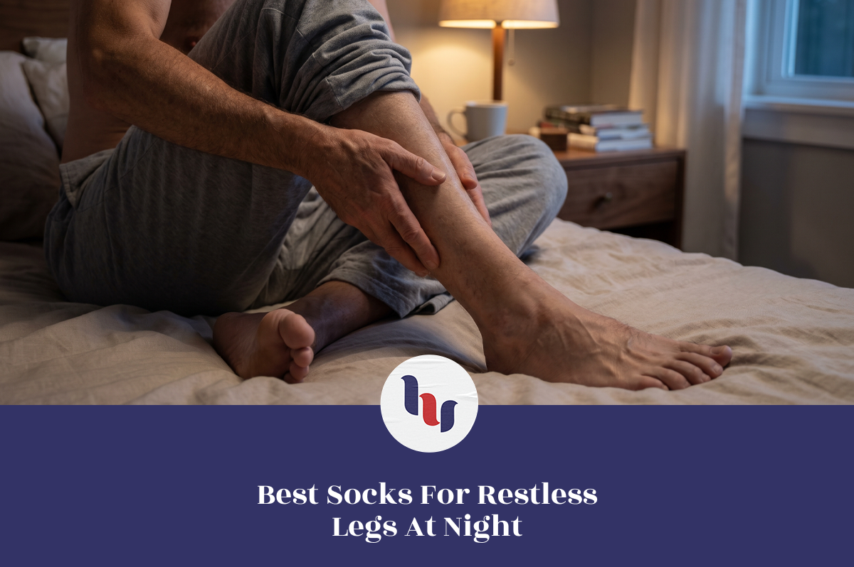 Man seated on a bed at night holding his lower leg and ankle.