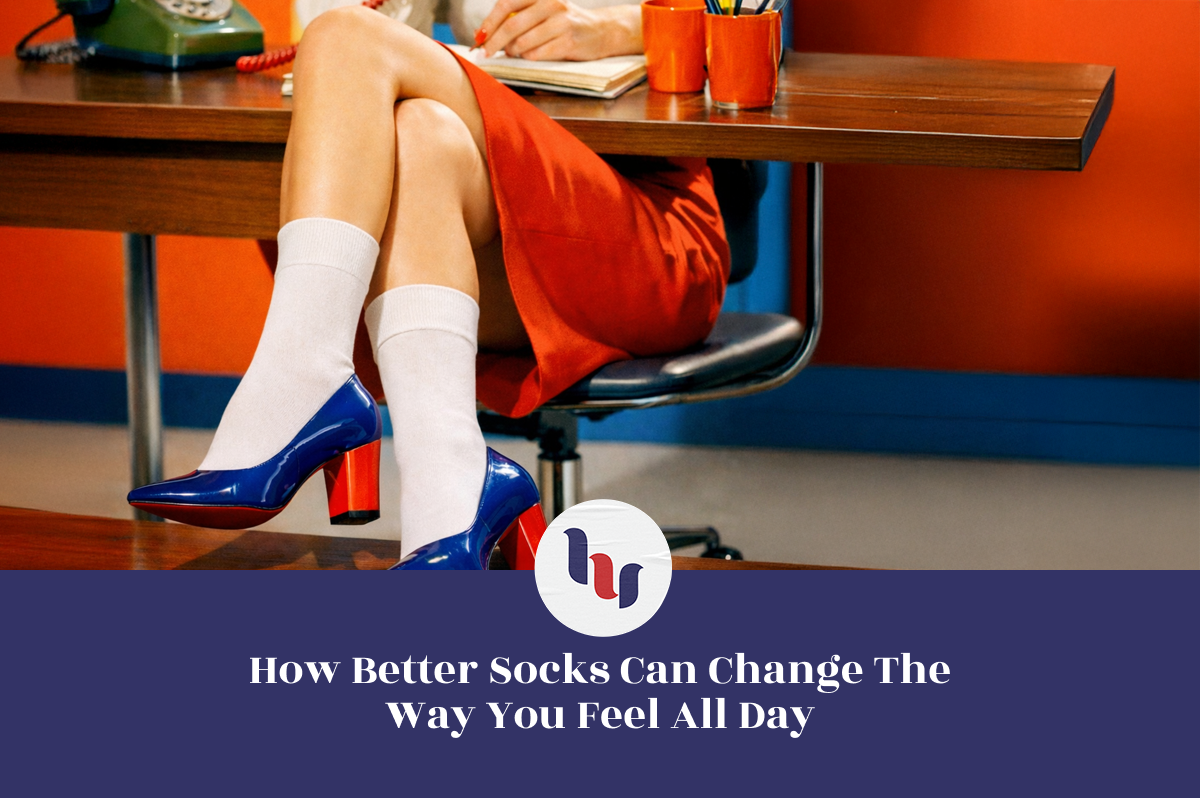 Person seated at a desk wearing white crew socks with blue high-heeled shoes, legs crossed in a retro office setting with warm colors and vintage details