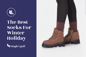 Brown winter boots with socks on a snowy ground, featuring Hugh & Goliath branding.