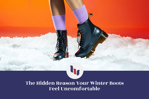 Person wearing black winter boots and purple socks on a snowy surface with an orange background.