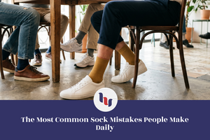 People sitting at a table with their feet showing, wearing different socks and shoes.