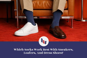 Person sitting on a chair wearing white sneakers, blue dress socks, and brown loafers with a red carpet background.