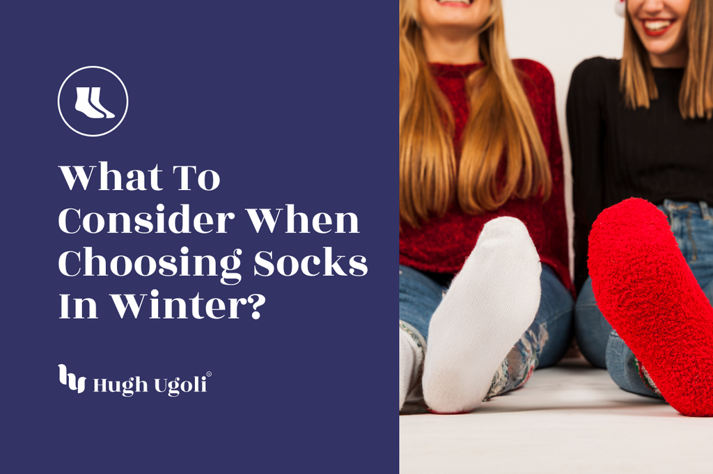 Two women in cozy winter attire, wearing colorful fluffy socks, sitting and smiling on a white floor. One wears red socks, and the other wears white, creating a warm and festive winter vibe.