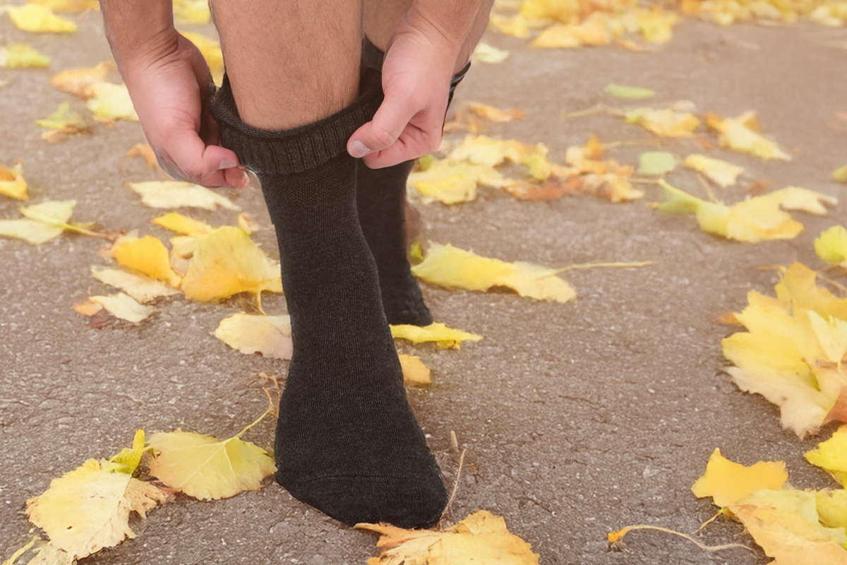 Person wearing black socks on a ground covered with yellow leaves