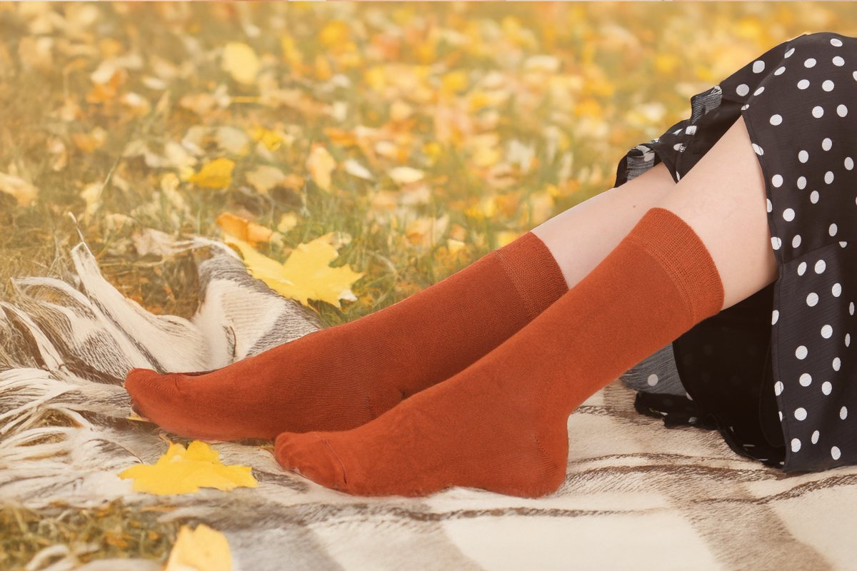 Person wearing orange knee-high socks with a blurred autumn background