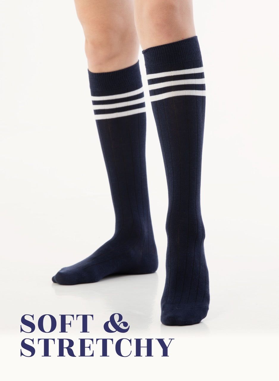 Navy knee-high socks with white stripes worn by a person on a white background, with text 'SOFT & STRETCHY' below.