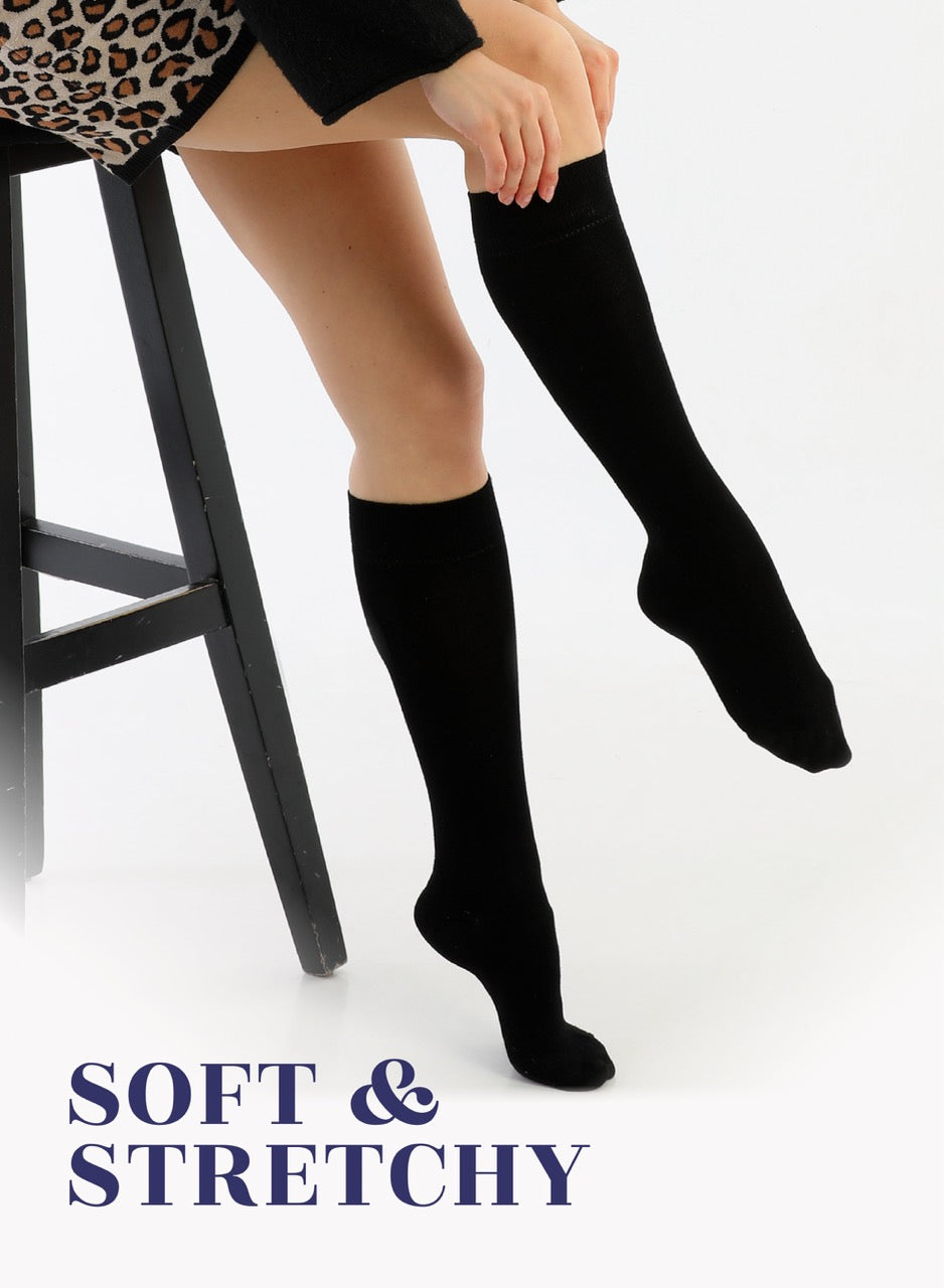 Person wearing black knee-high socks sitting on a stool with text 'Soft & Stretchy'.