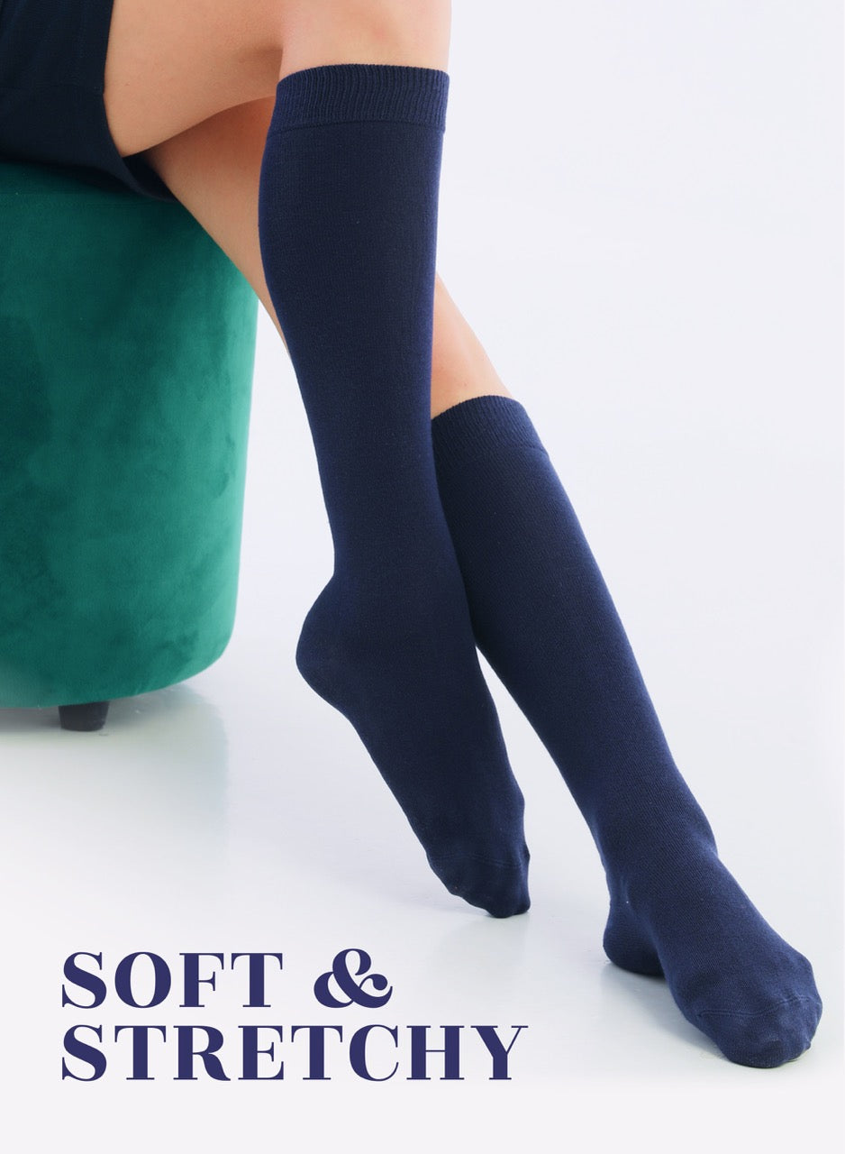 Navy blue knee-high socks worn by a person sitting on a green stool with 'Soft & Stretchy' text.