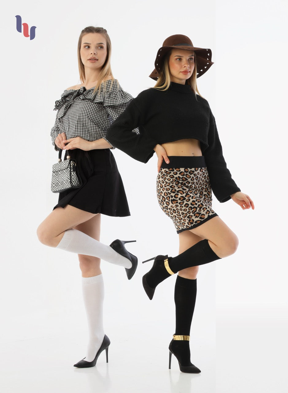 Two women posing in stylish outfits with a white background