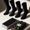 Four black socks with a colorful polka dot box on a light background