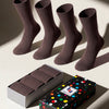 Four pairs of brown socks with a colorful polka dot box in the foreground.