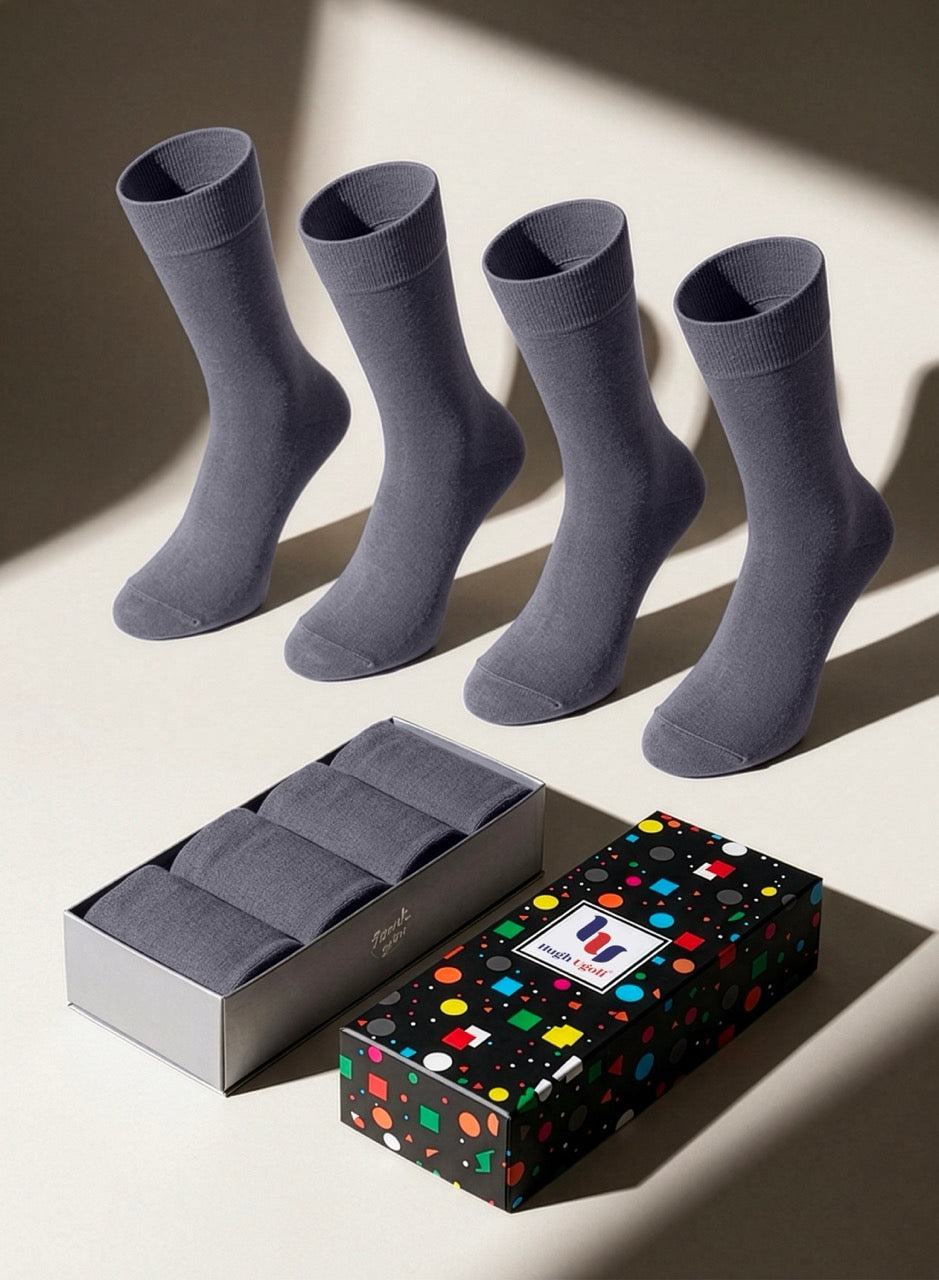 Four pairs of gray socks with a colorful polka dot gift box on a light background