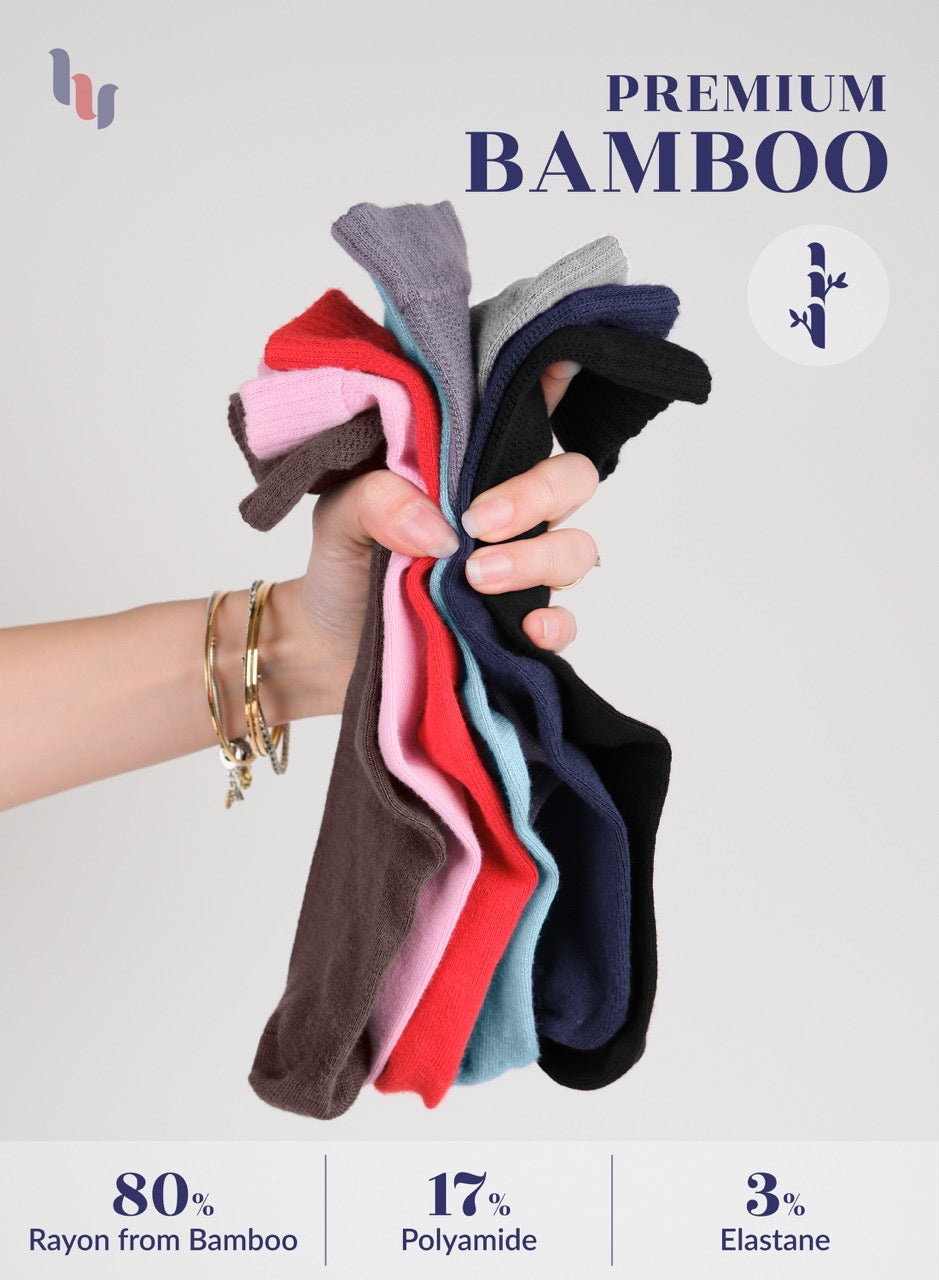 Hand holding a stack of colorful bamboo socks with product details on a light gray background