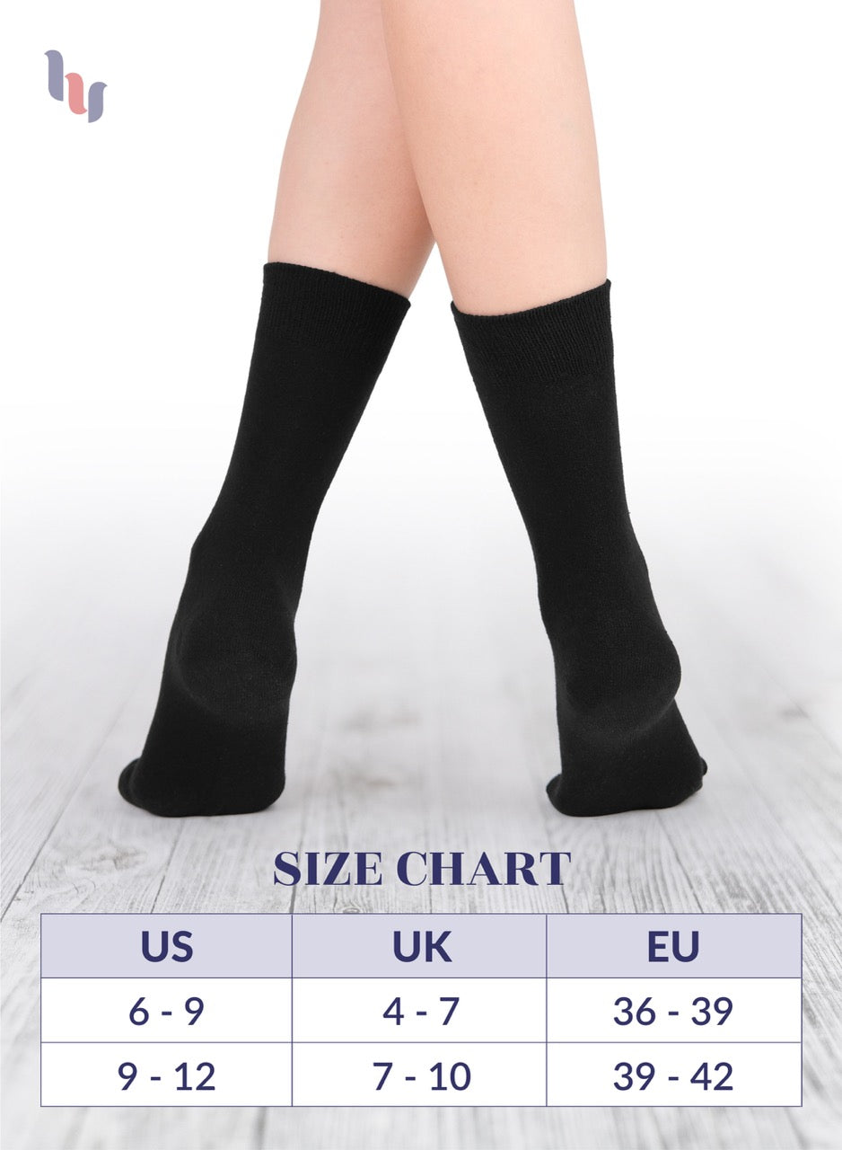 Black socks being worn with a size chart below on a light wooden floor.