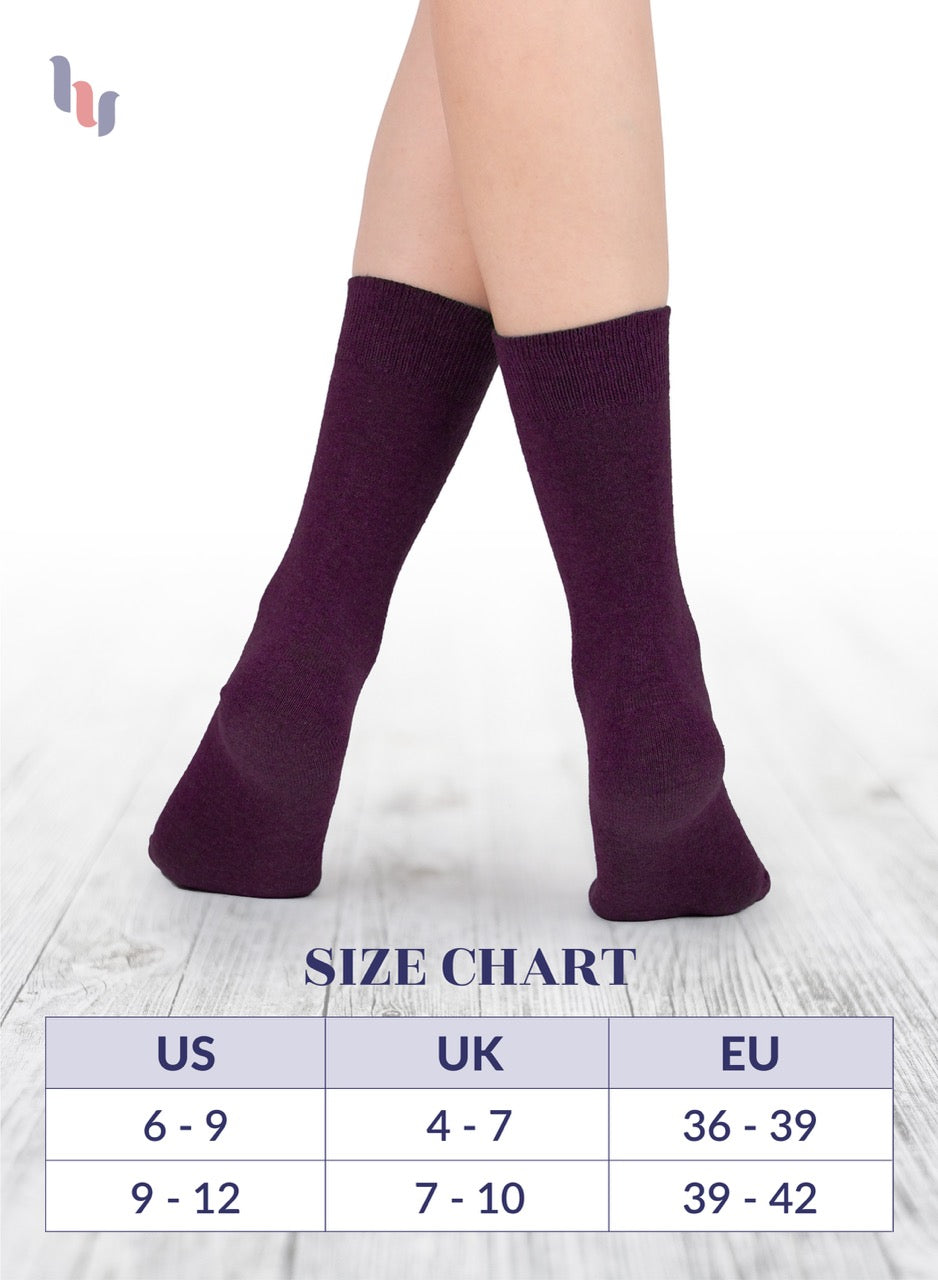 Grape knee-high socks on a person's legs with a size chart below on a light wooden floor.