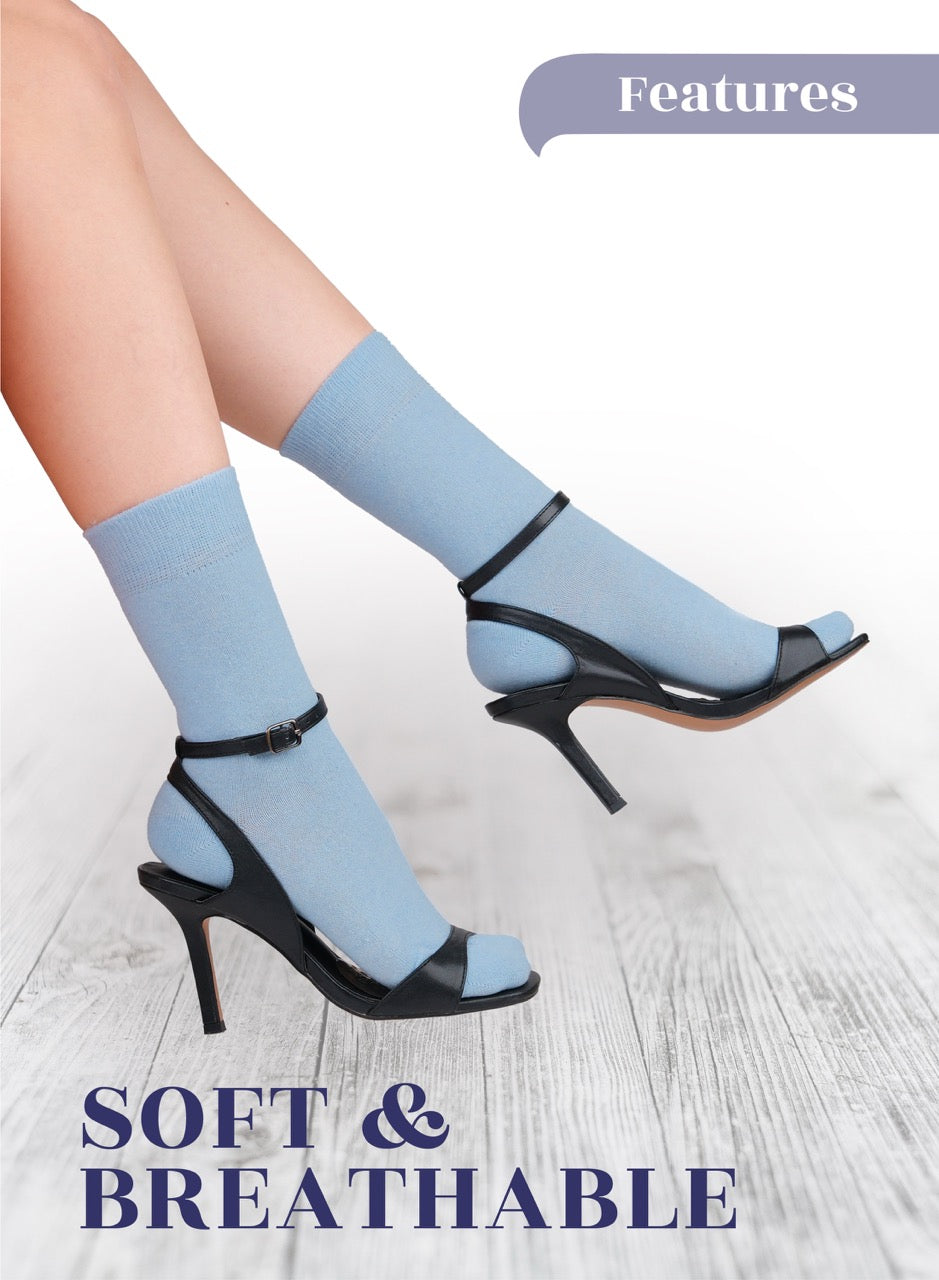 Blue socks worn with black high-heeled shoes on a light wooden floor.