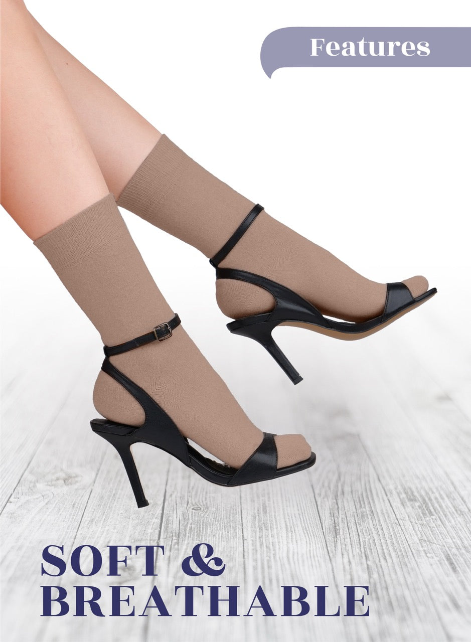 Black high-heeled sandals worn with coffee socks on a light wooden floor.