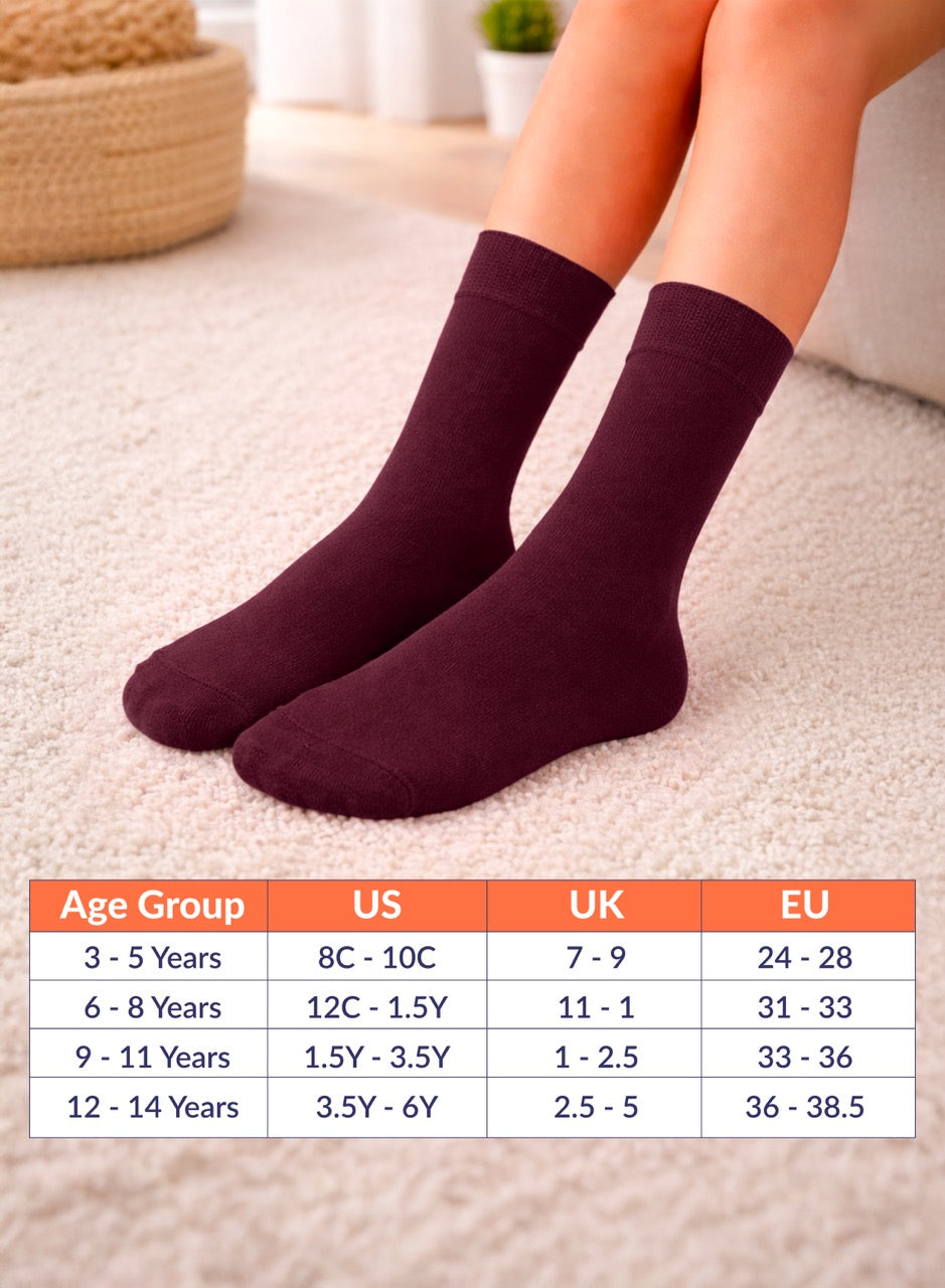 Burgundy socks on a person's feet with a size chart below on a carpeted floor.