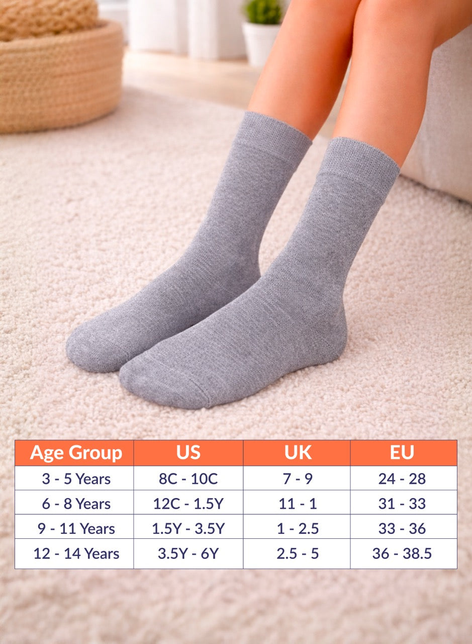Gray socks being worn with a size chart for children's feet on a carpeted floor.