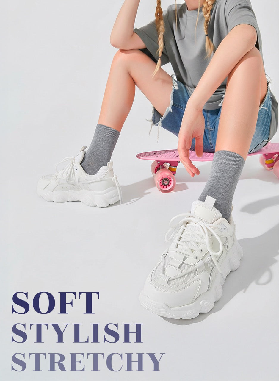 Person sitting on a pink skateboard wearing white sneakers, gray socks, and a gray shirt.