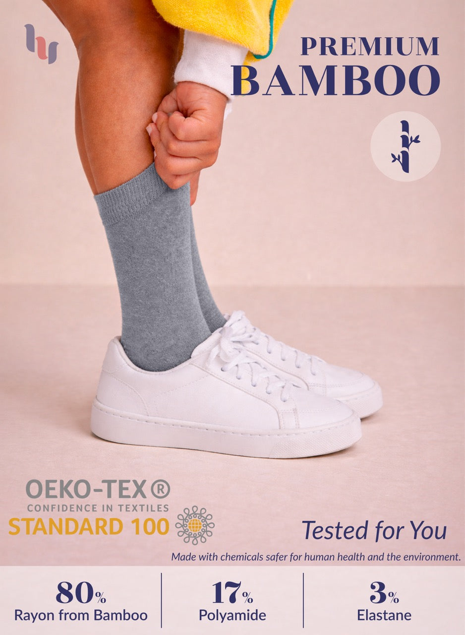 Person wearing gray socks and white sneakers with text about premium bamboo and OEKO-TEX certification on a beige background.