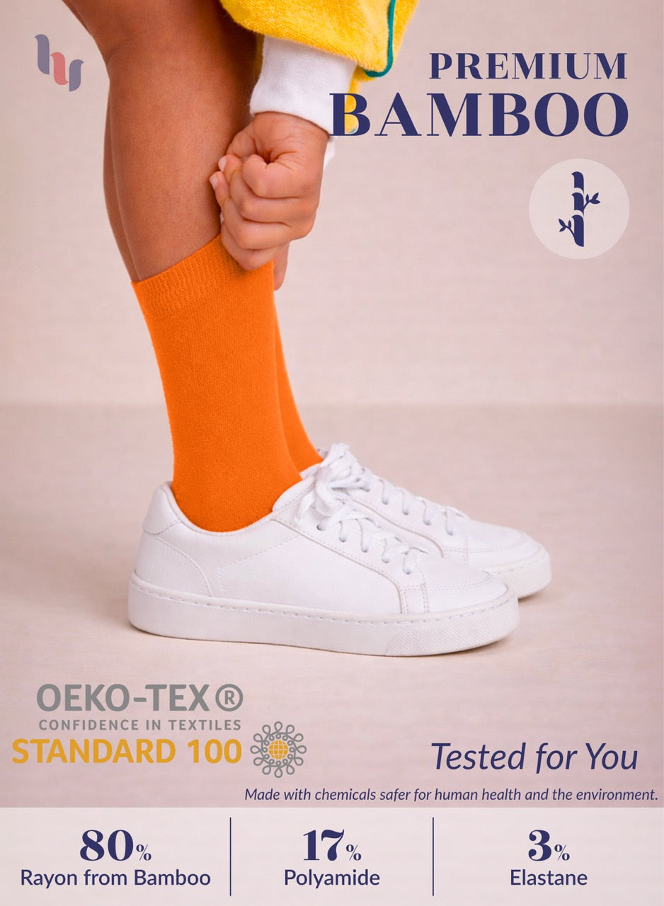 Person wearing pumpkin orange socks and white sneakers with text about premium bamboo socks and OEKO-TEX certification.