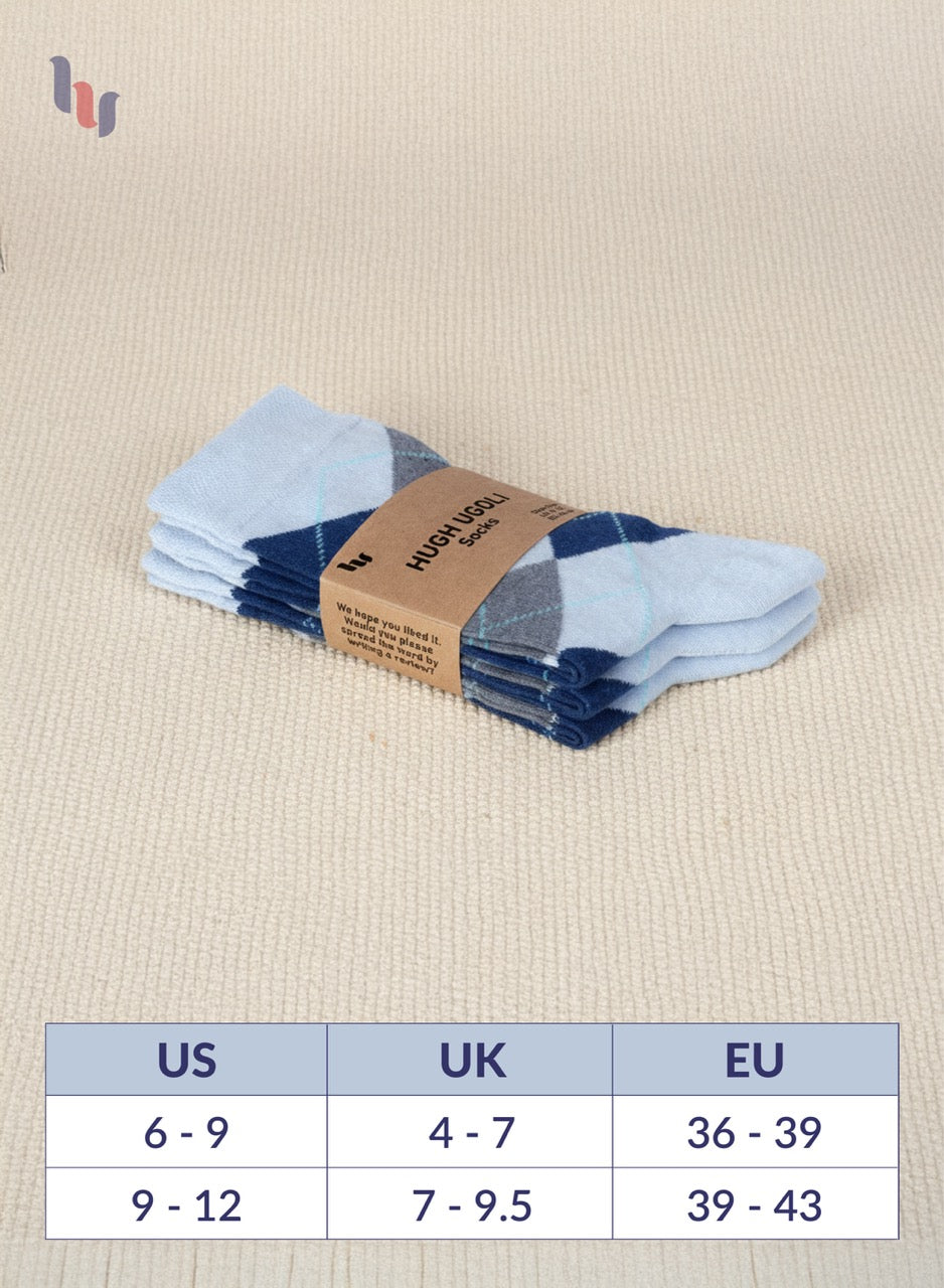 Stack of Blue socks with a cardboard label on a beige fabric background, featuring a size chart.