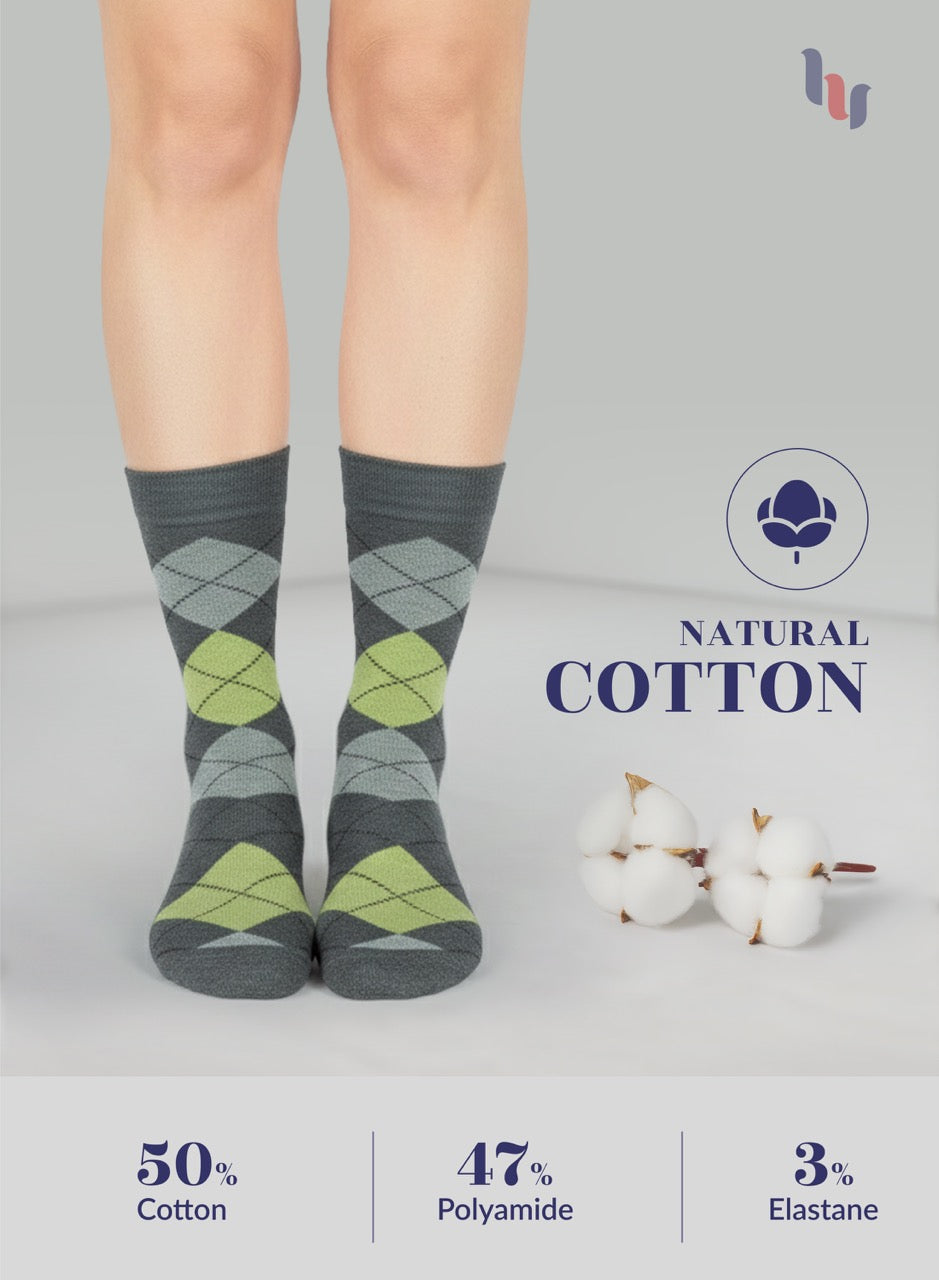 Gray argyle socks with green accents worn by a person, on a light gray background with cotton and brand logo.