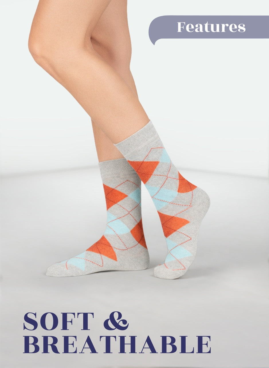 Light Grey argyle socks with orange and blue triangles worn by a person on a light gray background.