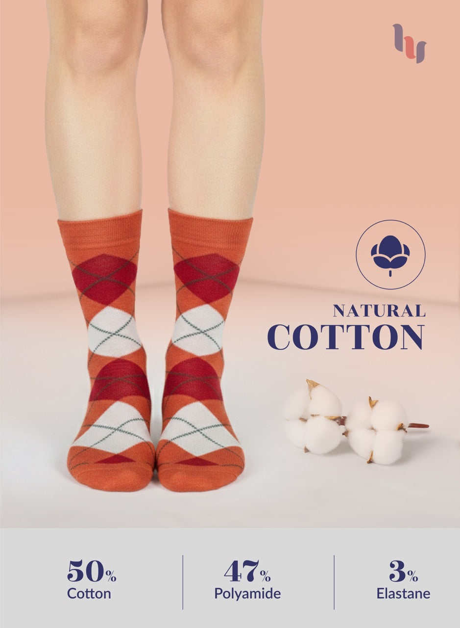 Orange argyle socks with natural cotton label and cotton fibers on a light background