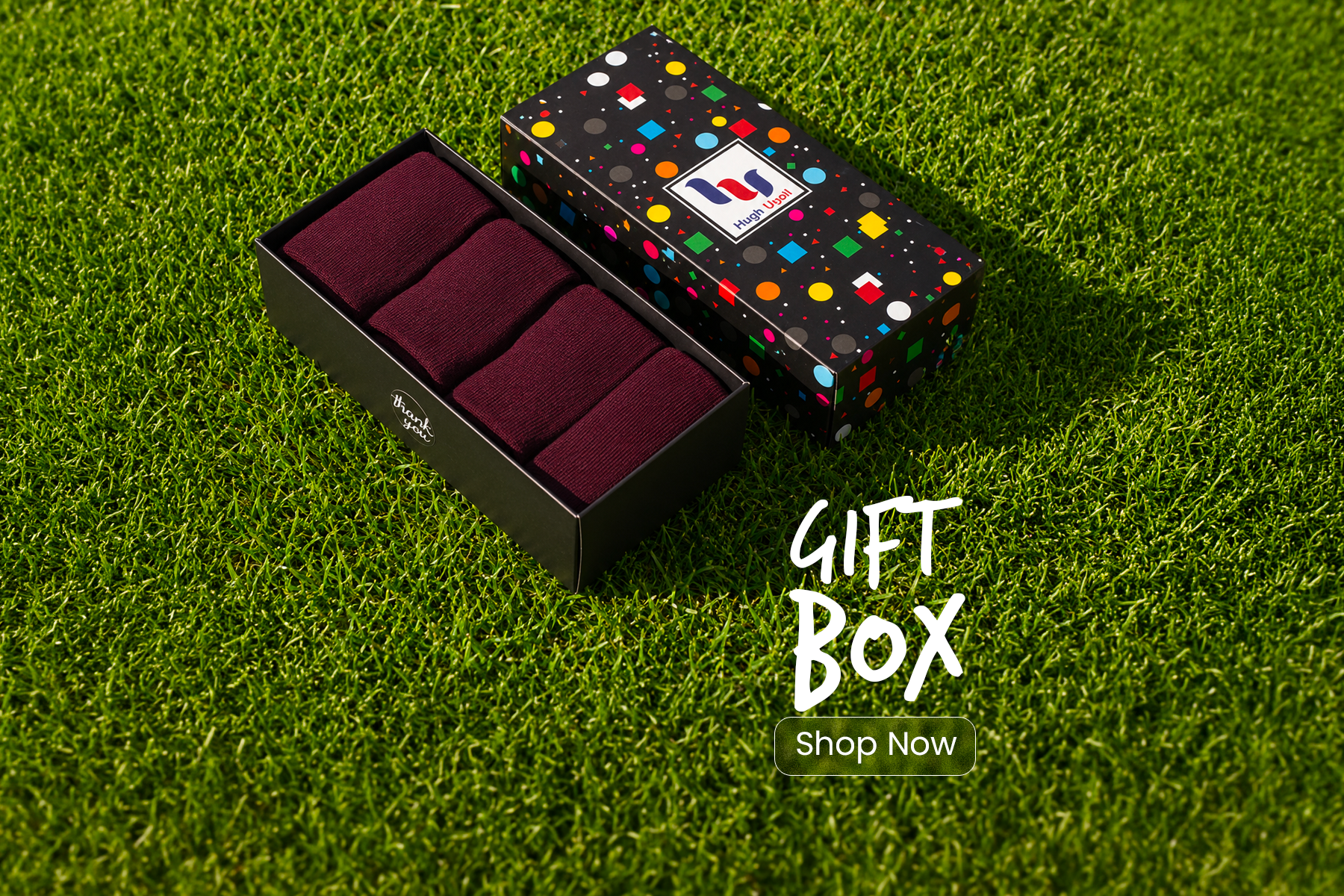 Gift box with polka dot design and red items on a grass background