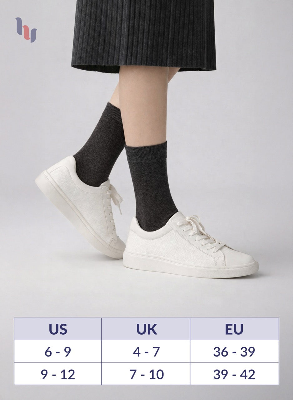 Person wearing Dark grey socks with white sneakers on a light gray background, with size chart below.