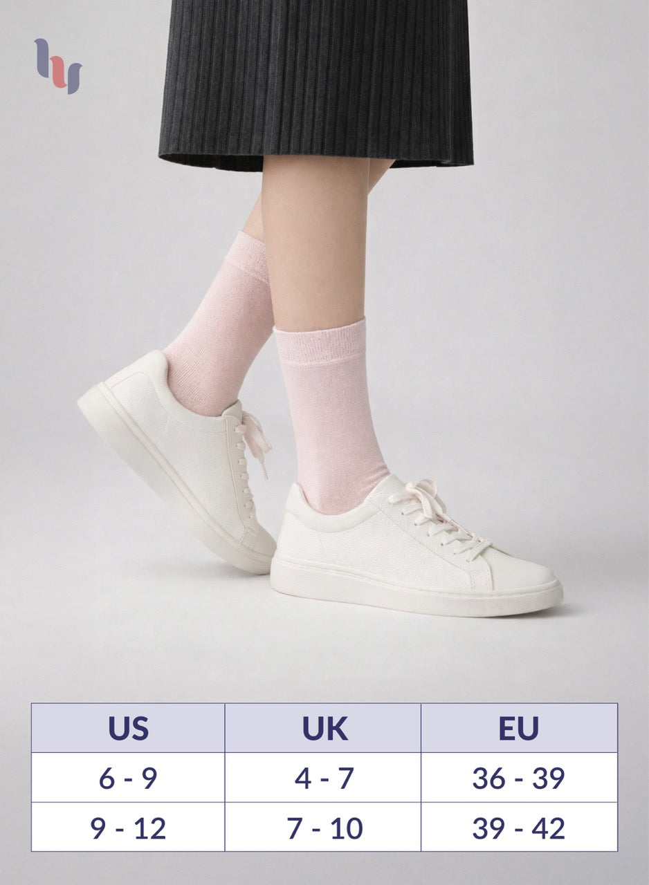 White sneakers worn with pink socks on a gray background, featuring a size chart.