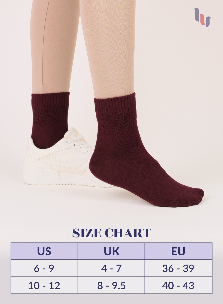 Burgundy socks being worn with a size chart on a light background