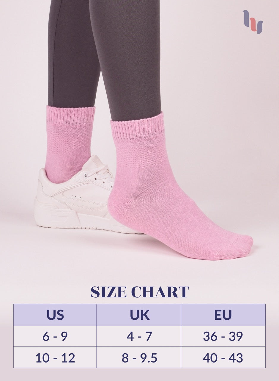 Pink socks worn with gray leggings and white sneakers on a light pink background, with a size chart below.