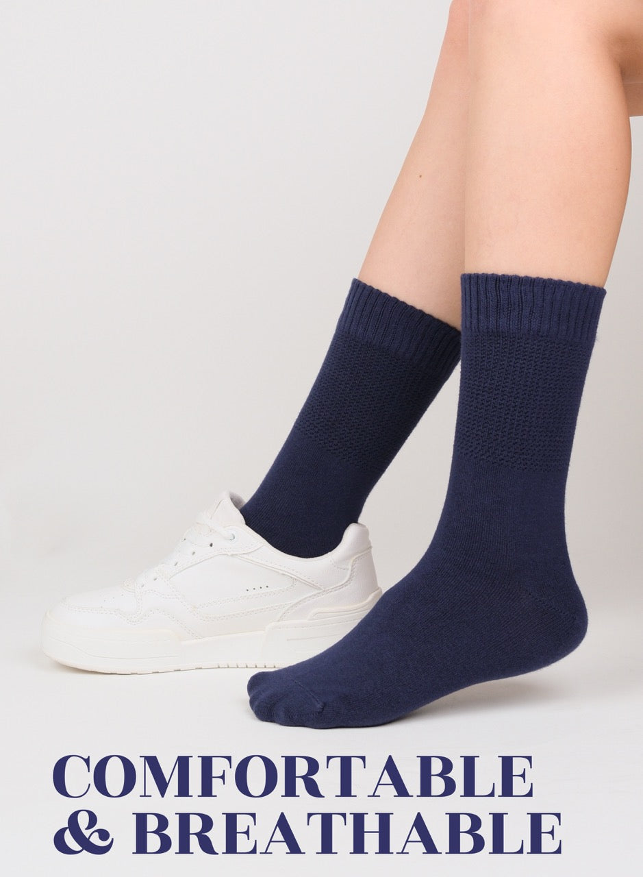 Navy blue socks worn with white sneakers on a light gray background