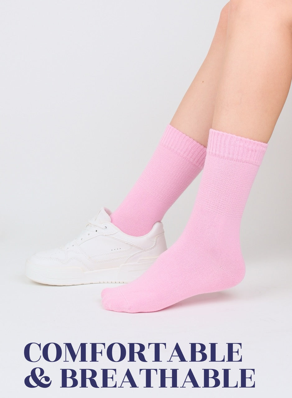 Pink socks worn with white sneakers on a light gray background