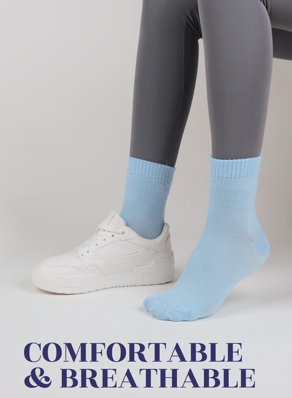 Person wearing sky blue socks with gray leggings and white sneakers on a plain background