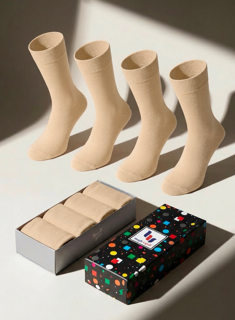 Four beige socks on a light surface with a colorful box in the foreground.