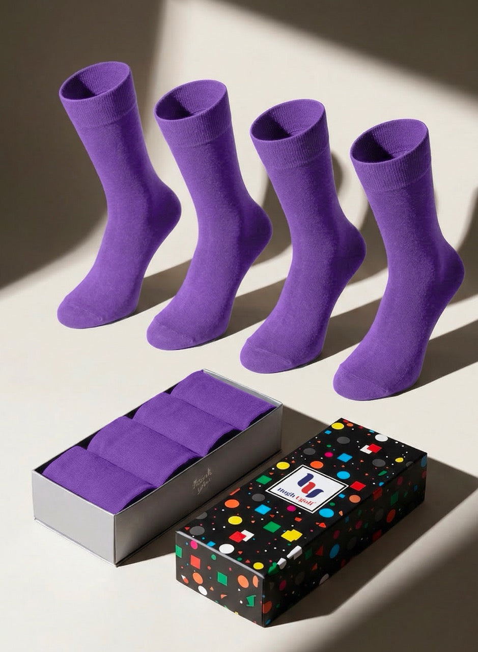 Four purple socks on a light surface with a branded box in the foreground.