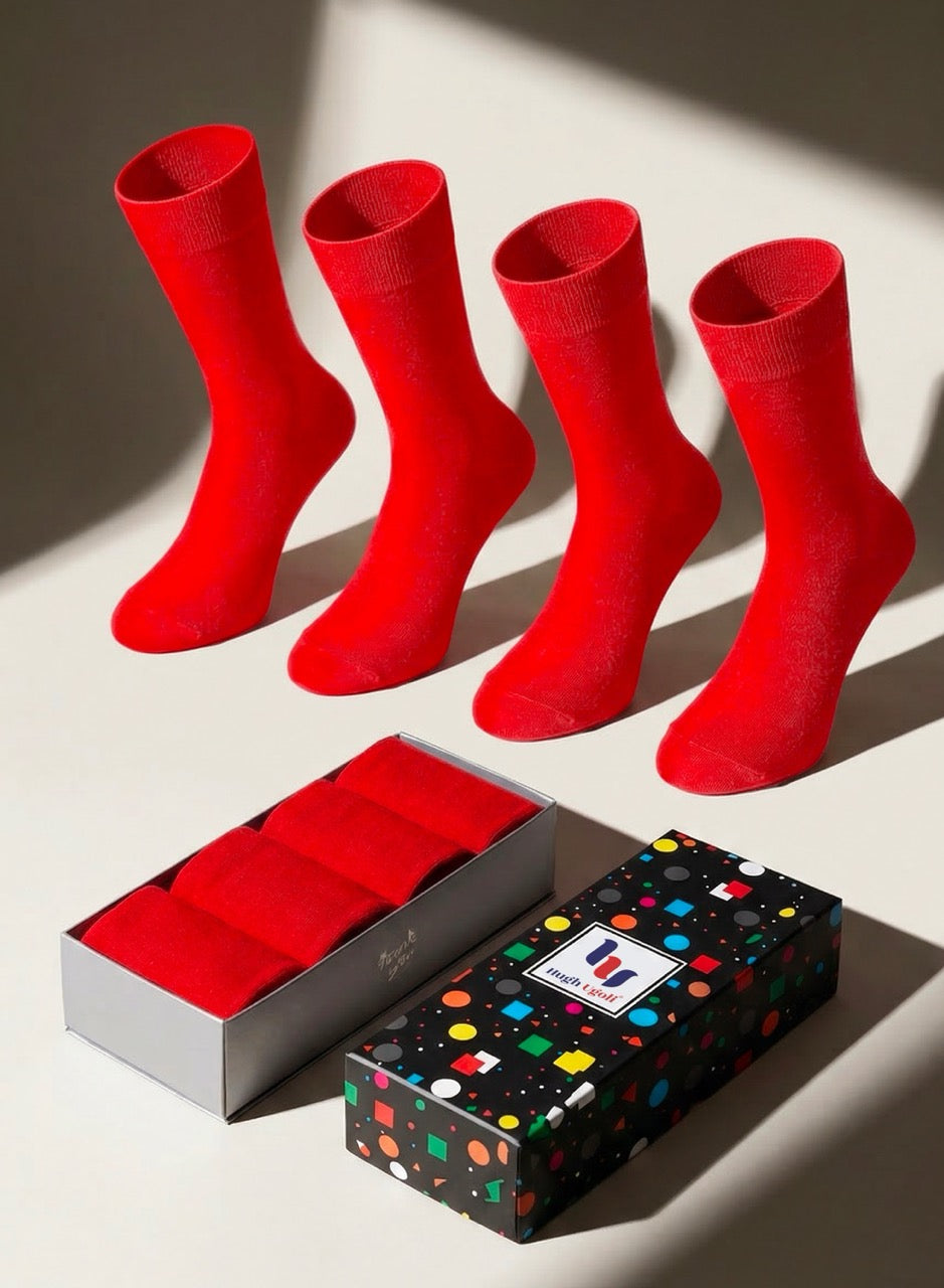 Four red socks on a light surface with a patterned gift box.
