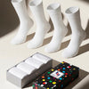 Four white socks with a colorful polka dot box on a light background