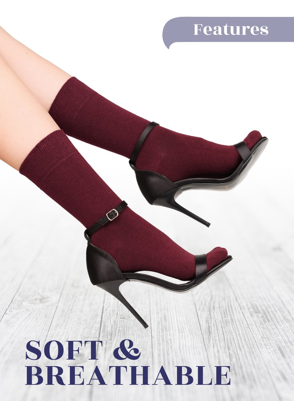 Burgundy socks high-heeled shoes with maroon socks on a light wooden floor.