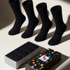 Four black socks with a colorful polka dot box on a light background