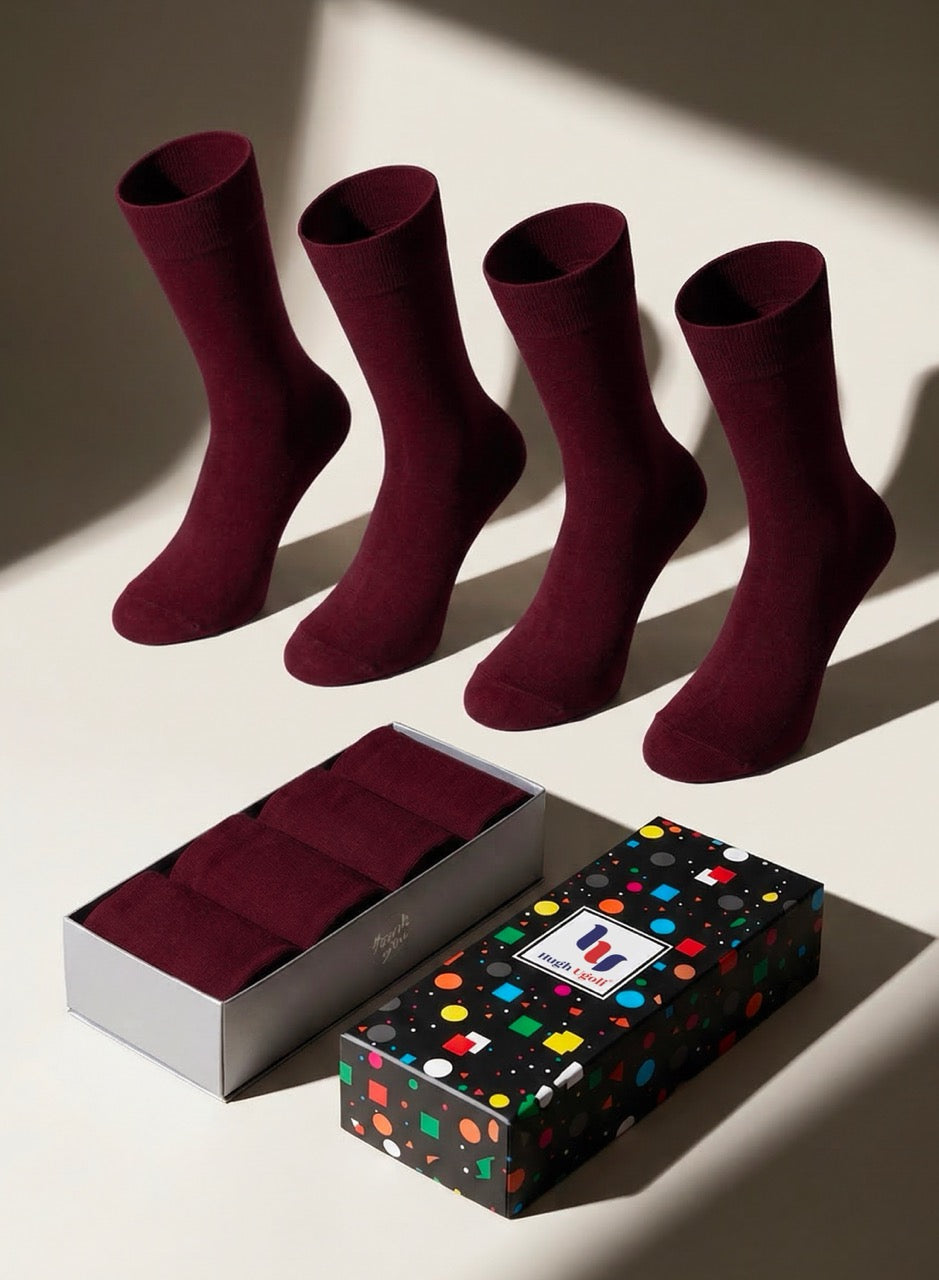 Set of burgundy socks with a colorful polka dot box on a light background