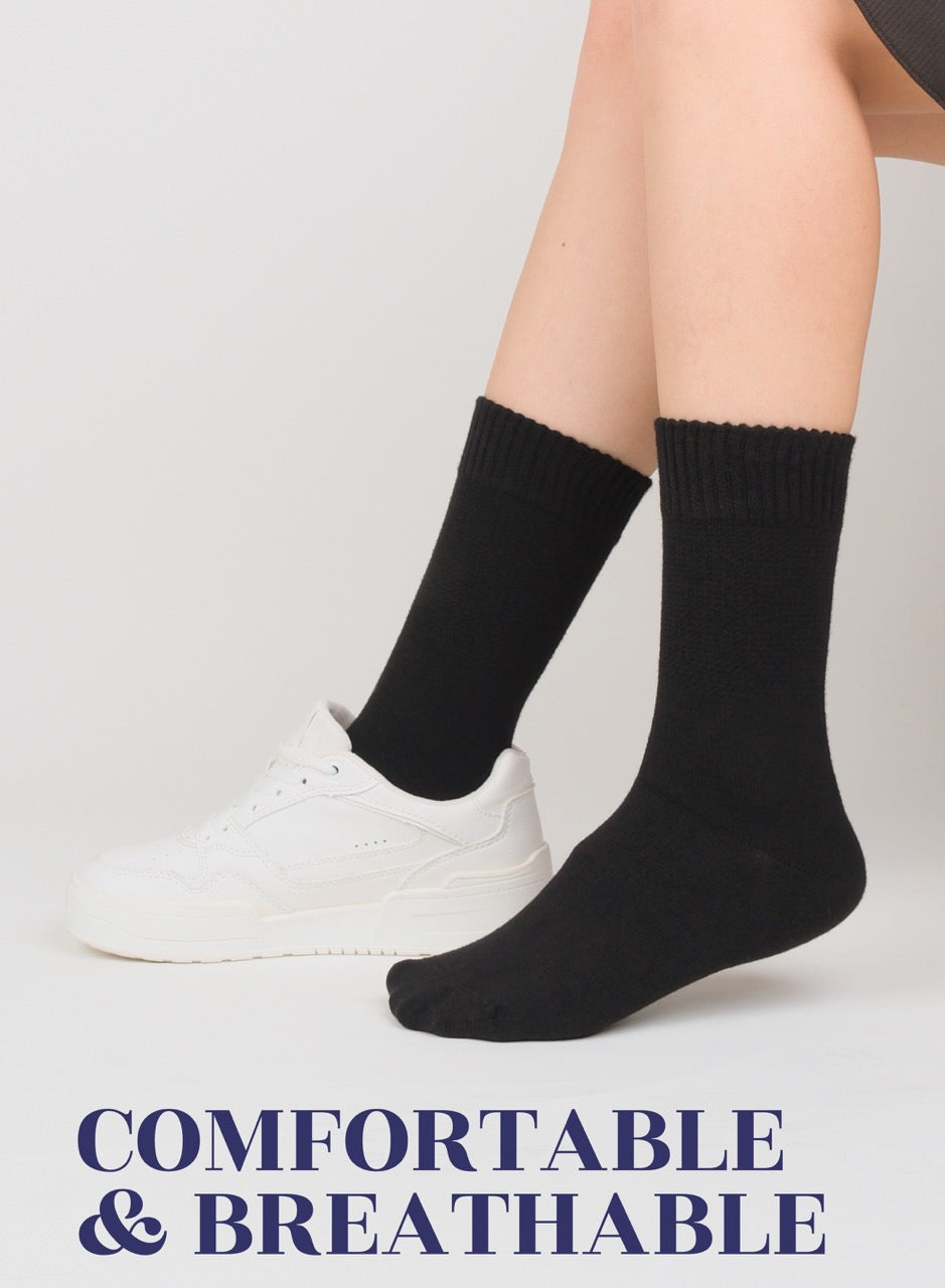 Person wearing black socks with white sneakers on a light gray background