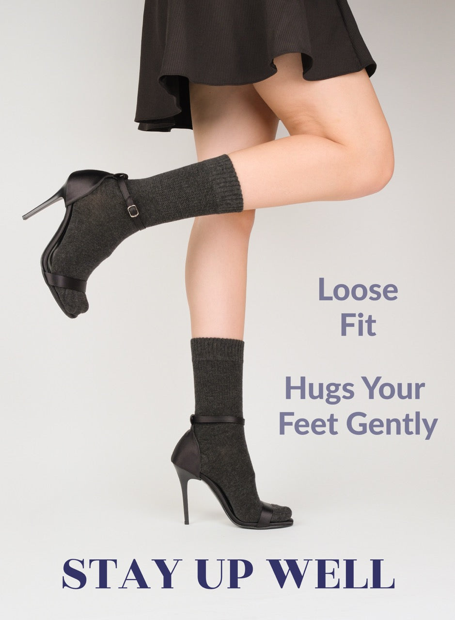 Person wearing black high-heeled shoes and charcoal socks with text about sock fit on a light gray background