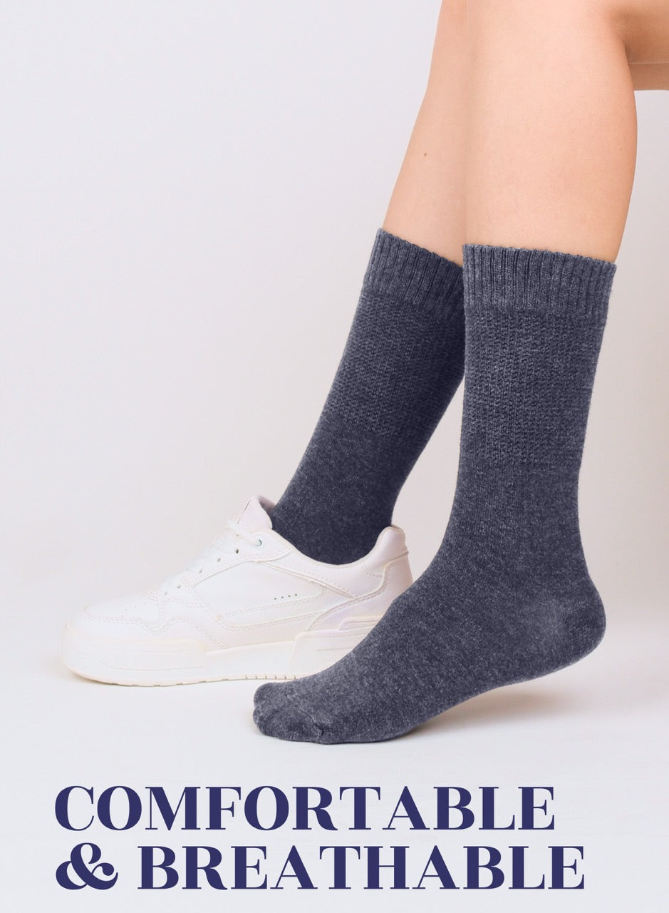 Person wearing indigo blue socks with text 'COMFORTABLE & BREATHABLE' on a light background