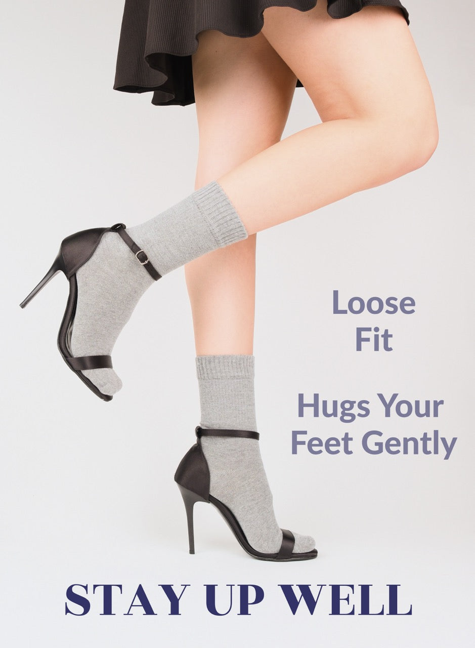 Person wearing high-heeled shoes with light gray socks on a light background, promoting 'Stay Up Well' brand.